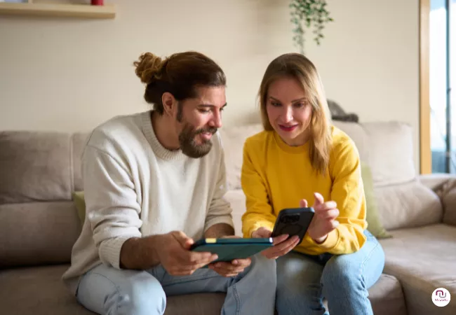 Potentielle Kunden (Frau und Mann) vergleichen Preise am Smartphone und Tablet